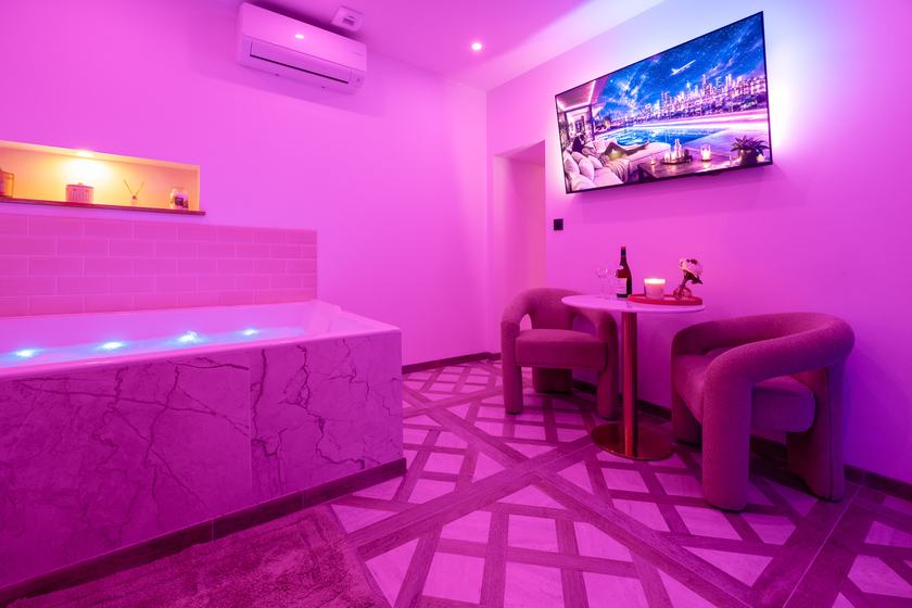 Wellness Spa à Dijon : jacuzzi en marbre clair, coin salon et écran mural